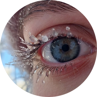 Mavi insan gözünün və islanmış kirpiklərin yaxın plan fotosu, üzərində üzmə və ya göz yaşlarını xatırladan aydın su damcıları var.