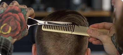 Profesyonel bir kuaförün makas ve tarak kullanarak geçişli bir saç modeli oluşturduğu yakın çekim görüntüsü.