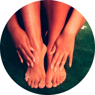 Yaşıl, teksturlu səth üzərində bir insanın əli ilə çılpaq ayaqlarını və ayaqlarını toxunduğu yaxın plan kadr, rutin gözəllik proseduru, pedikür və ya ayaq masajı təsiri yaradır.